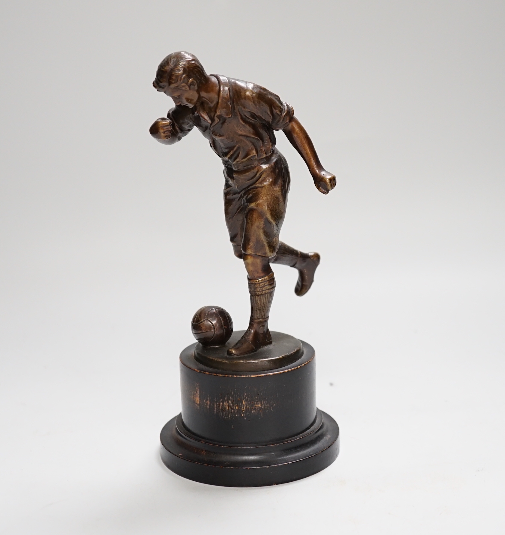 A pre-war bronze figure of a footballer, raised on a circular ebonies wood base, 23cm high